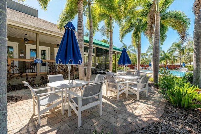 view of patio / terrace featuring outdoor dining space, fence, a community pool, and a ceiling fan