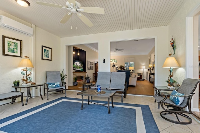 sitting room with a ceiling fan, a warm lit fireplace, a wall mounted air conditioner, and light tile patterned floors