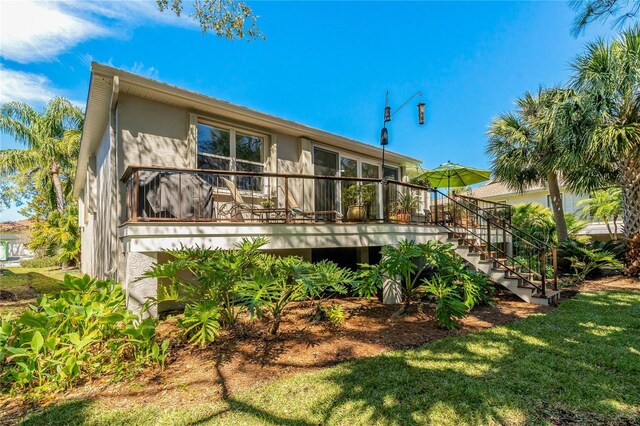 rear view of property with a yard, stairway, a wooden deck, and stucco siding