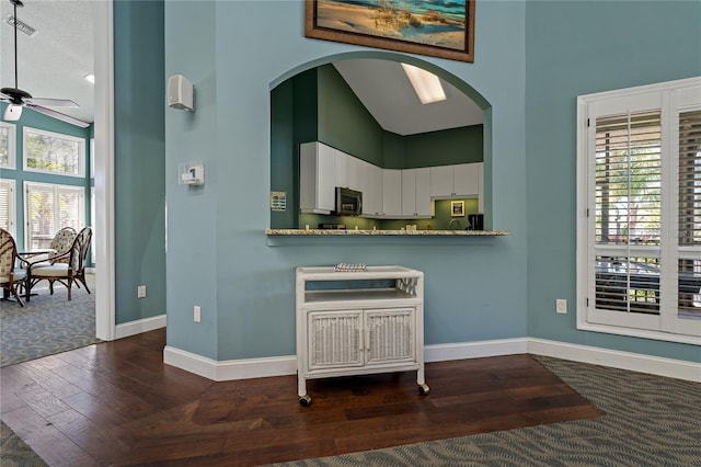 kitchen with white cabinetry, high vaulted ceiling, baseboards, and stainless steel microwave