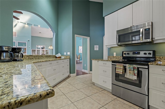 kitchen featuring light tile patterned floors, stainless steel appliances, white cabinetry, and light stone countertops