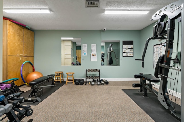 workout area with visible vents, a textured ceiling, and baseboards