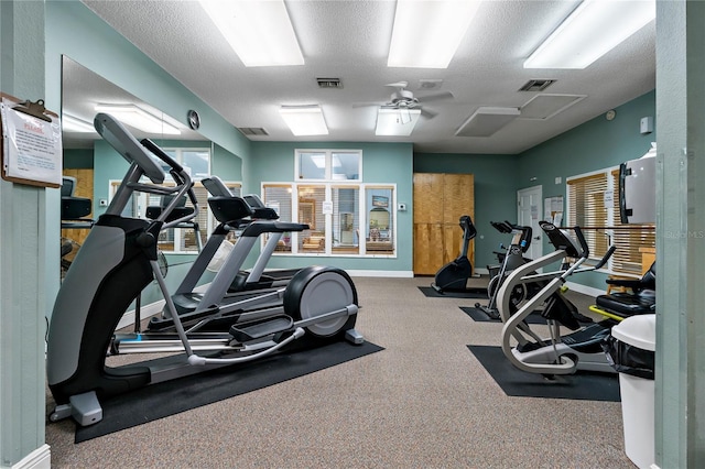 exercise room with visible vents, a textured ceiling, and baseboards