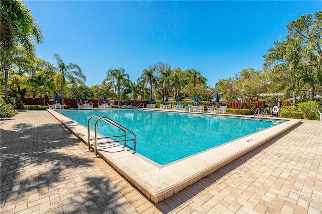 community pool with a patio area and fence