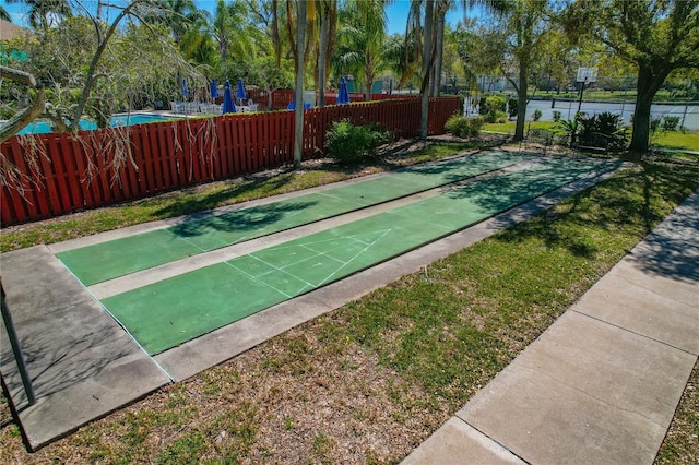 view of community featuring shuffleboard, fence, and a yard