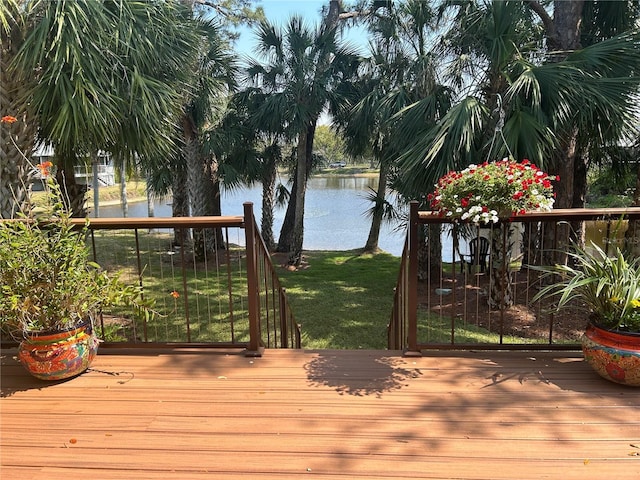 wooden deck with a water view and a lawn