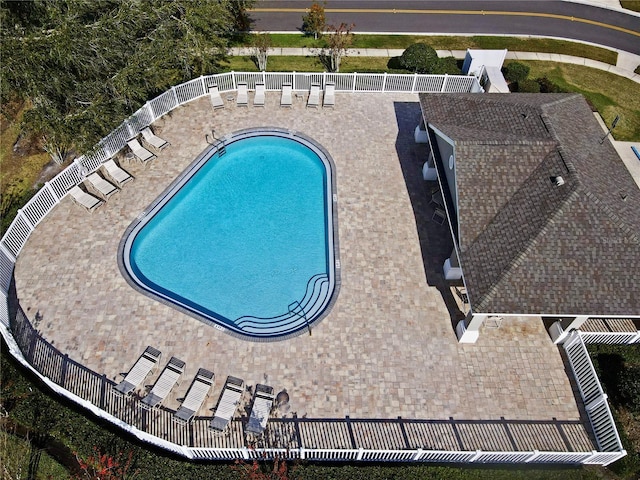 community pool with a patio area and fence