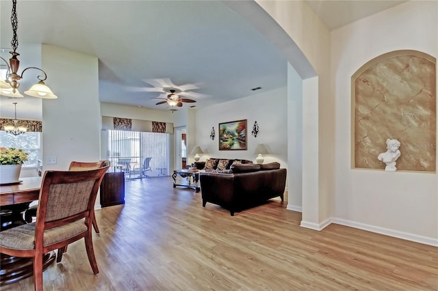 living room with baseboards, visible vents, light wood finished floors, and ceiling fan with notable chandelier