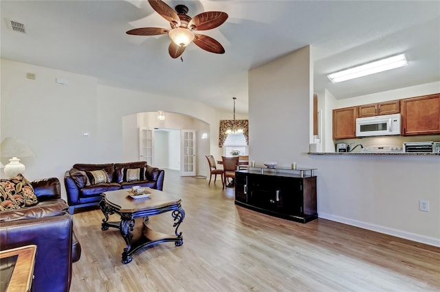 living area featuring arched walkways, a toaster, visible vents, a ceiling fan, and light wood-type flooring