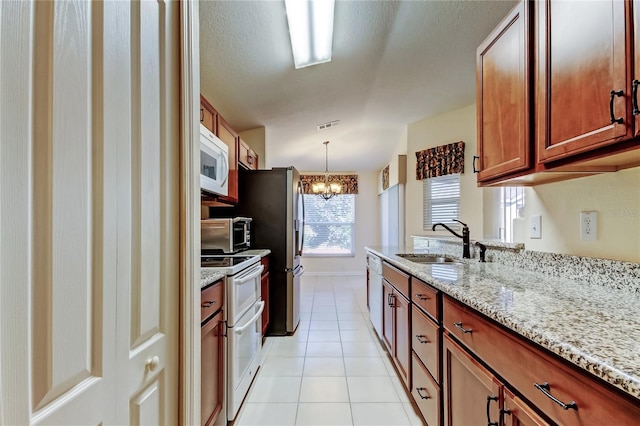 kitchen featuring light tile patterned flooring, a notable chandelier, white appliances, a sink, and light stone countertops