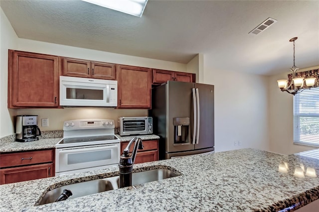 kitchen featuring a toaster, visible vents, hanging light fixtures, light stone countertops, and white appliances