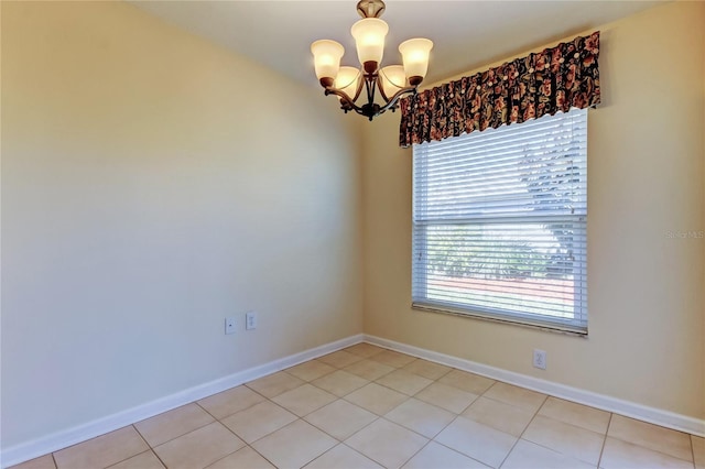 unfurnished room featuring an inviting chandelier, baseboards, and light tile patterned flooring