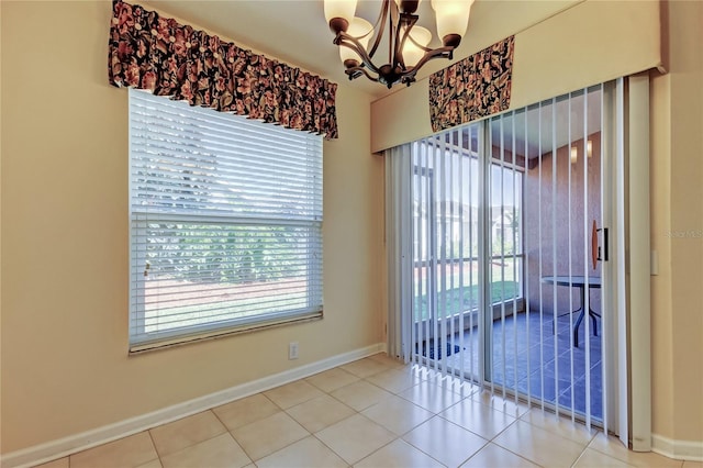 unfurnished room with a chandelier, tile patterned flooring, plenty of natural light, and baseboards