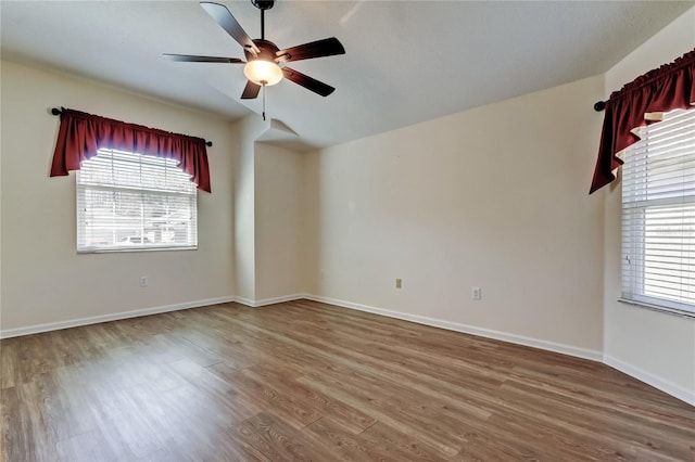 empty room with a ceiling fan, baseboards, and wood finished floors