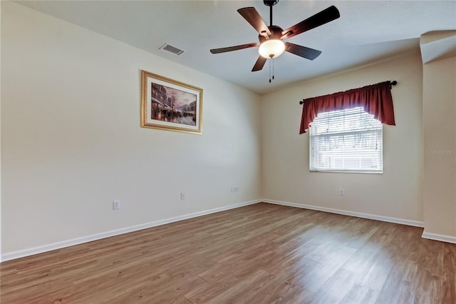 empty room featuring a ceiling fan, wood finished floors, visible vents, and baseboards