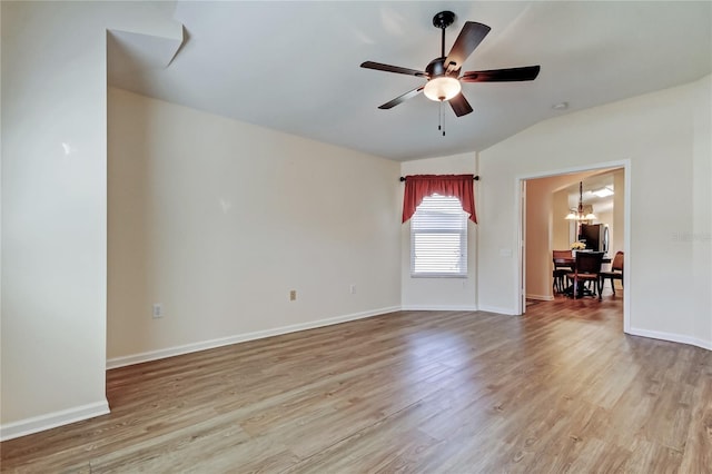 empty room featuring lofted ceiling, light wood-style floors, baseboards, and ceiling fan with notable chandelier