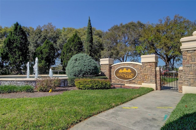 community / neighborhood sign with a gate and a lawn