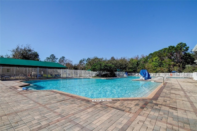 pool with a patio area and fence