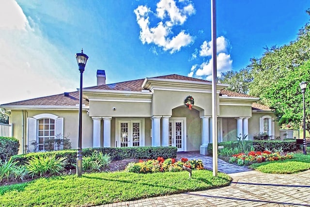 mediterranean / spanish-style home with french doors, a chimney, and stucco siding