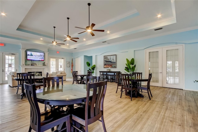 dining space featuring french doors, a fireplace, a raised ceiling, and visible vents