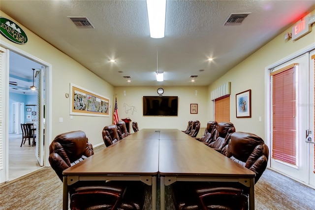 dining area with visible vents, a textured ceiling, and carpet flooring