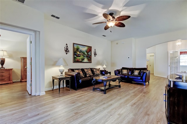 living area featuring arched walkways, visible vents, baseboards, a ceiling fan, and light wood-type flooring