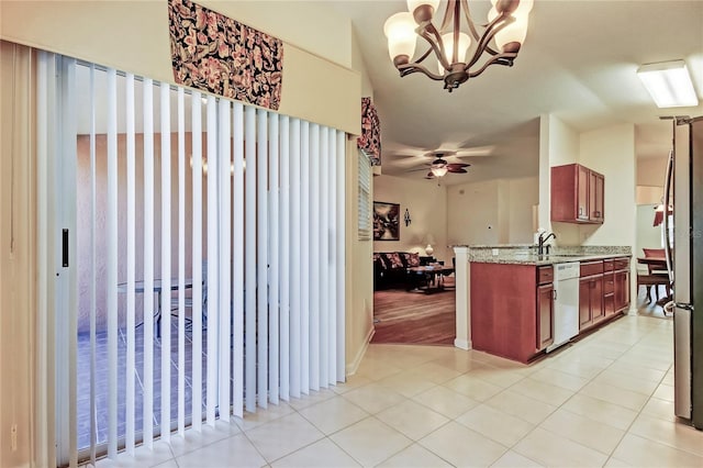 kitchen featuring light tile patterned floors, dishwasher, light stone countertops, a sink, and ceiling fan with notable chandelier