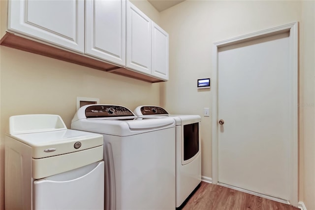 laundry area featuring light wood-type flooring, cabinet space, and washing machine and dryer