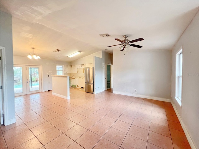 unfurnished living room with ceiling fan with notable chandelier, french doors, light tile patterned flooring, baseboards, and vaulted ceiling