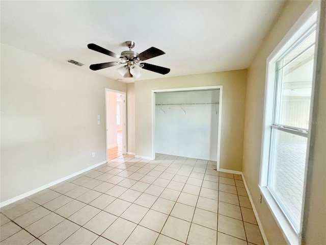 unfurnished bedroom featuring light tile patterned floors, a closet, visible vents, ceiling fan, and baseboards