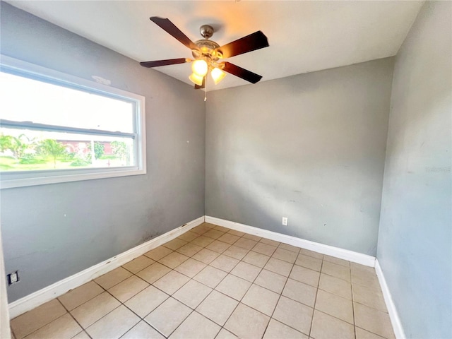 spare room with light tile patterned floors, a ceiling fan, and baseboards