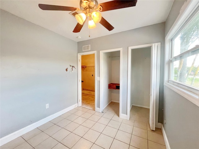 unfurnished bedroom with light tile patterned floors, baseboards, visible vents, and a ceiling fan