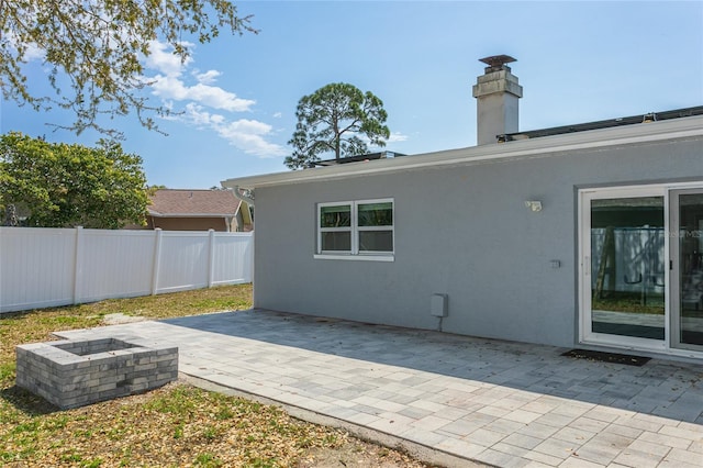 back of property with stucco siding, an outdoor fire pit, a patio area, and fence