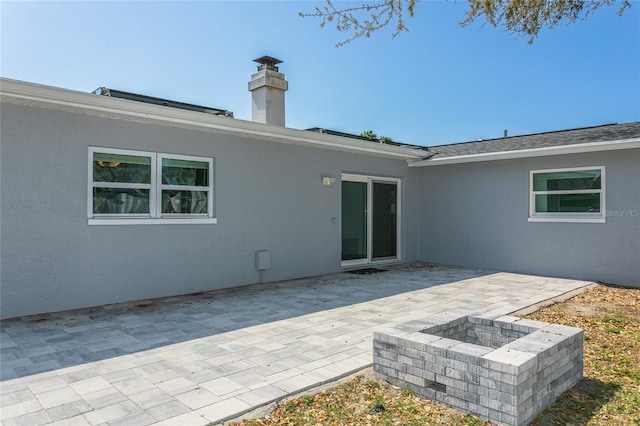 back of property featuring stucco siding, a patio, and a fire pit