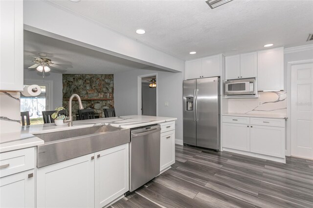 kitchen featuring a sink, backsplash, stainless steel appliances, white cabinets, and ceiling fan