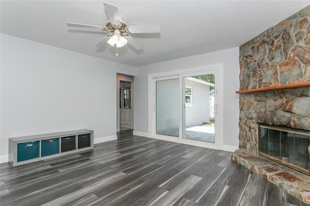 unfurnished living room featuring dark wood finished floors, a fireplace, baseboards, and a textured ceiling