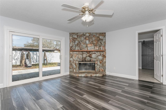 unfurnished living room with a barn door, a textured ceiling, and wood finished floors