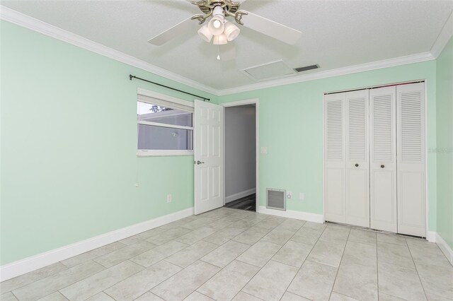 unfurnished bedroom with visible vents, attic access, a closet, and crown molding