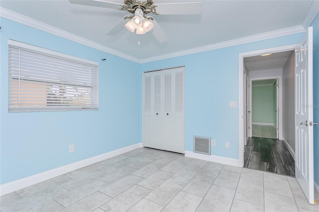 unfurnished bedroom featuring crown molding, baseboards, visible vents, and a closet