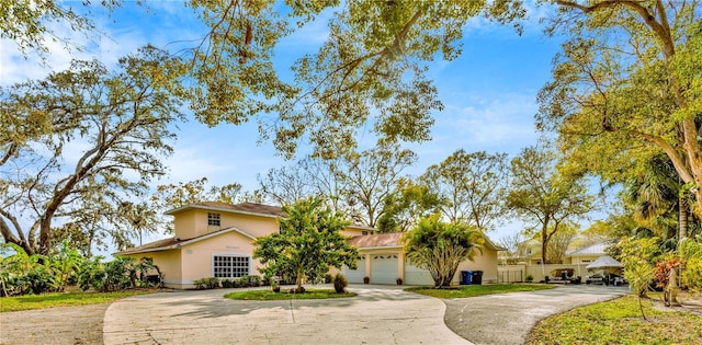 view of front facade with stucco siding, concrete driveway, and fence