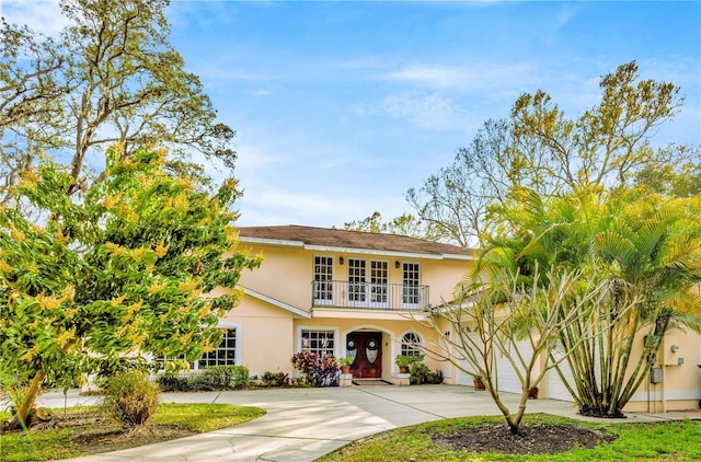 view of front of home featuring a balcony, driveway, stucco siding, french doors, and a garage