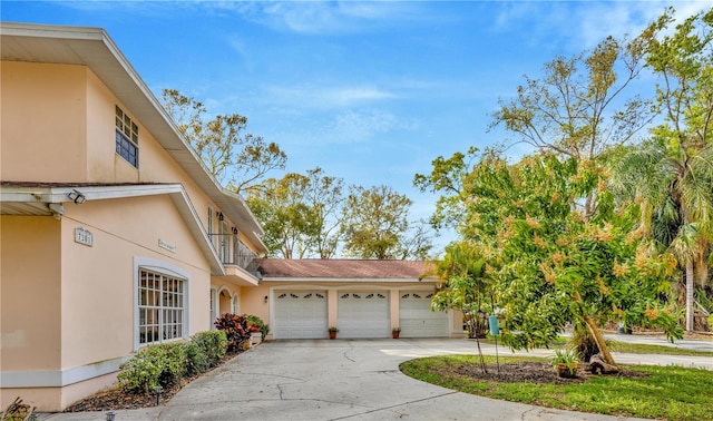 view of front of property featuring stucco siding, concrete driveway, and a garage