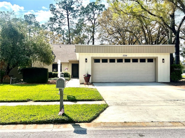 view of front of home featuring an attached garage, a shingled roof, driveway, board and batten siding, and a front yard