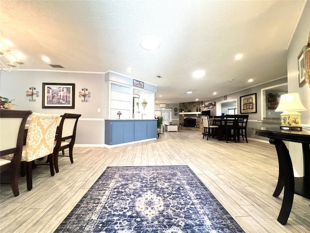 dining room with a textured ceiling, ornamental molding, and light wood finished floors