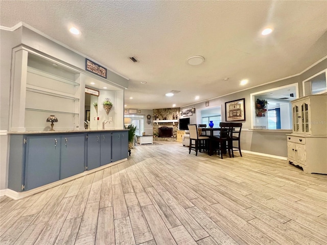 kitchen featuring a textured ceiling, a fireplace, and light wood finished floors