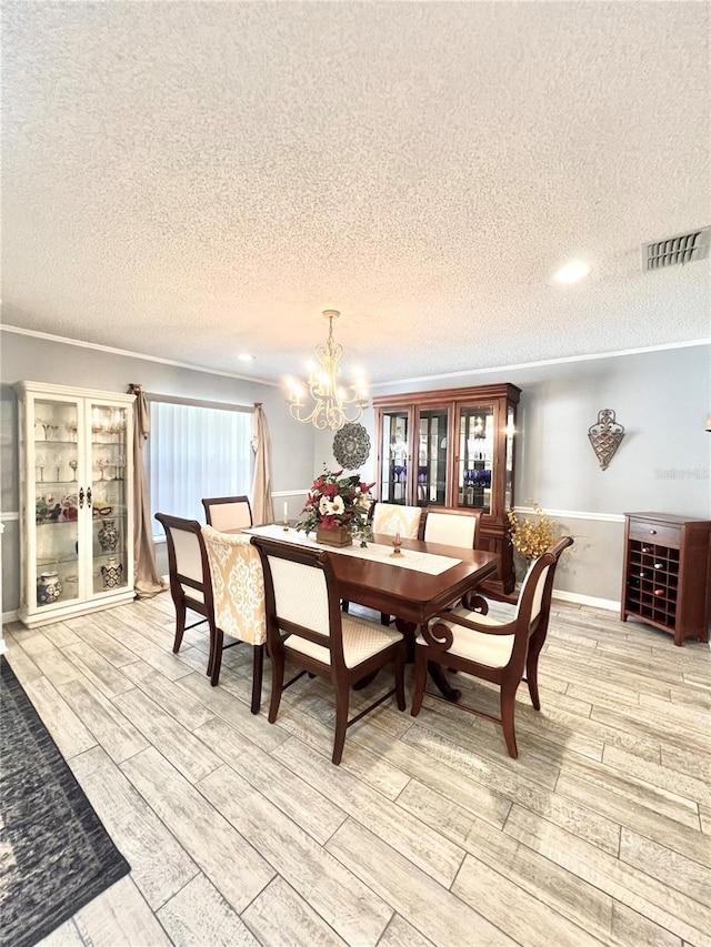 dining area featuring a notable chandelier, visible vents, wood finish floors, and ornamental molding