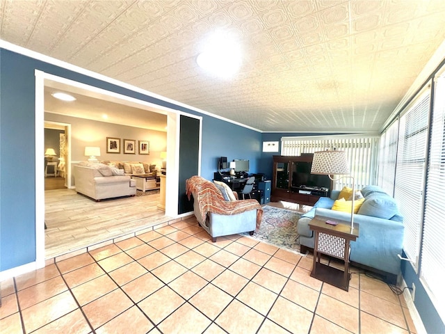 living area featuring crown molding, light tile patterned flooring, baseboards, and an ornate ceiling