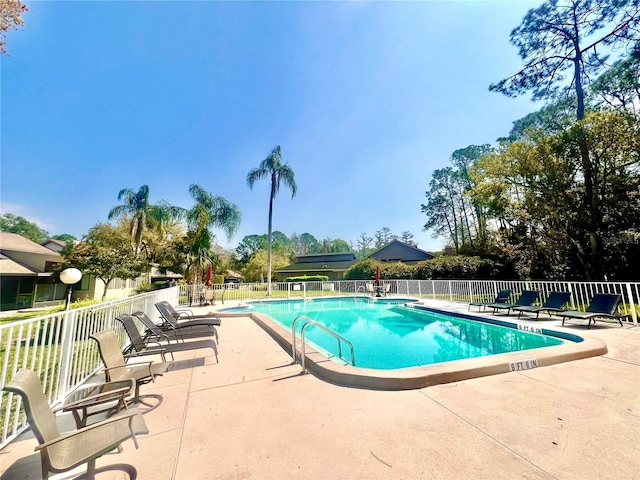 pool with a patio area and fence