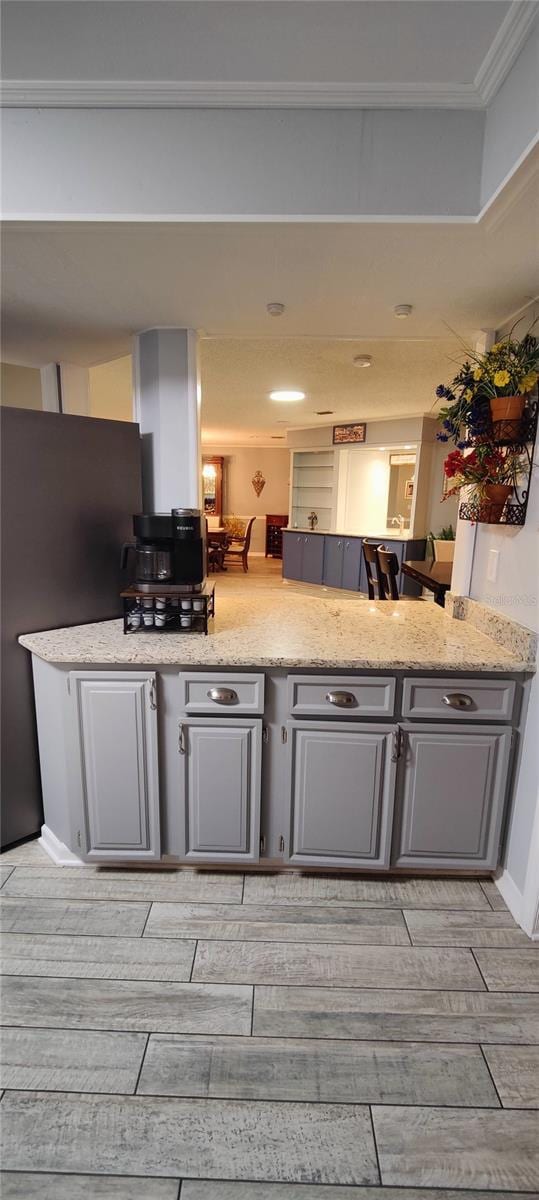 kitchen with light stone counters, gray cabinetry, wood tiled floor, and freestanding refrigerator