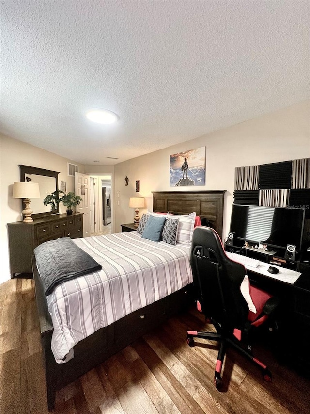 bedroom with wood finished floors, visible vents, and a textured ceiling